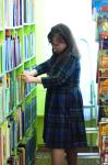 Библиотекарь Гульмира Рахметулловна внимательно ищет книги по запросу посетителя