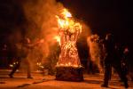 Авторы проекта синхронно осыпают горящую фигуру мелкими опилками