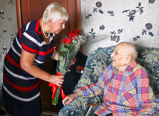 Цветы 104-летнему омичу Акиму Покатило вручает заместитель мэра Омска Ирина Касьянова